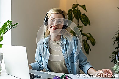 Head shot young happy woman sitting at desk, working on computer at home. Pleasant attractive smiling lady looking at Editorial Stock Photo
