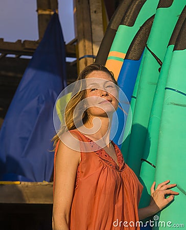 Head and shoulders portrait of young beautiful and happy blond woman smiling relaxed and cheerful posing with colorful surf boards Stock Photo