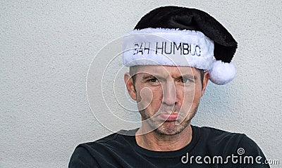Pouting Caucasian man in a black and white Bah Humbug hat Stock Photo