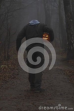 Headless man with Halloween pumpkin in foggy forest Stock Photo