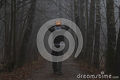 Headless man with Halloween pumpkin in foggy forest Stock Photo