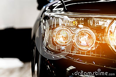 Headlight lamp of the new black luxury car, Close up detail on one of the LED headlights with flare of modern car. Stock Photo