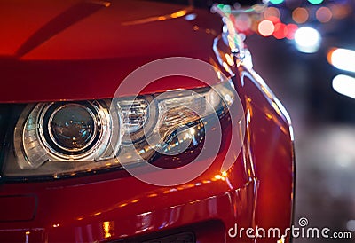 Headlights and hood of sport red car. evening city. Automobile detail close-up Stock Photo