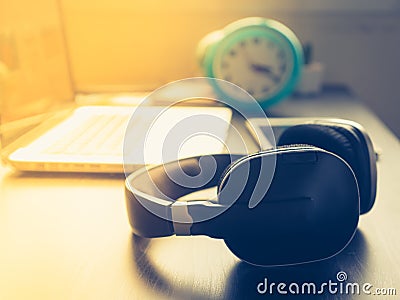 Headphone with Laptop on office desk and sunshine in afternoon Stock Photo