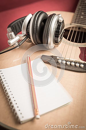 Headphone and Notebook and pencil on guitar Stock Photo