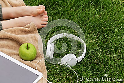 Headphones, electronic tablet and green apple for picnic in park Stock Photo