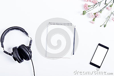 Headphones, smart phone, paper notebook, pencil and flowers lie Stock Photo