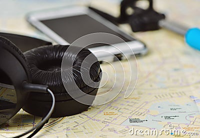 Headphones, smartphone and selfie stick on a map Stock Photo