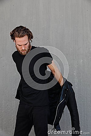 Headshot of handsome young bearded man wearing biker leather jacket. Vertical. Stock Photo