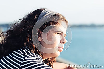 Headshot portrait of beautiful girl looking at the sea against sun Stock Photo