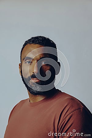 headshot portrait of a handsome thoughtful bearded mid adult man looking at camera against gray background Stock Photo