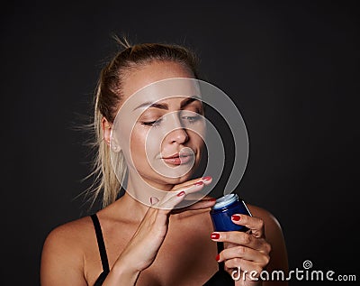 Closeup stunning beautiful middle aged European blonde woman applying face moisturizer, smoothing serum, taking care of facial Stock Photo