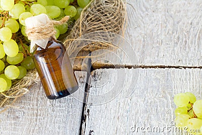 Healing grapes seeds oil in a glass jar, fresh grapes on old wooden background, seed extract has antioxidant and nourishing the sk Stock Photo