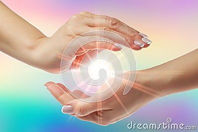 Healing hands with bright sunburst on rainbow background Stock Photo