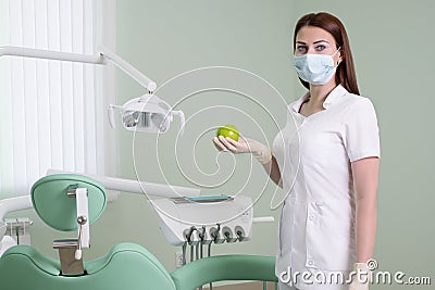 People, medicine, dentistry and healthcare concept - happy young female dentist with green apple in hand on background of medical Stock Photo