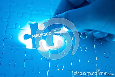 Health Care Concept. Doctor holding a jigsaw puzzle with MEDICAID word. Stock Photo