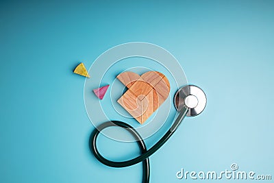 Health Care Concept. International World Heart Day. Wooden Jigsaw as Heart Shape with Stethoscope lay on Blue background. Life, Stock Photo