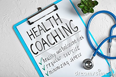 Health coaching written on sheet of paper with stethoscope on white textured background Stock Photo