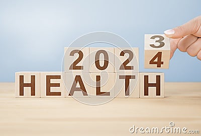 2024 health concept. Hand flip wooden cube change year 2023 to 2024. gray background, copy space. Hand flip wooden cube change on Stock Photo