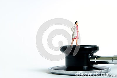 Health conceptual miniature people photography â€“ women doctor stands above stethoscope Stock Photo