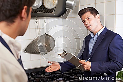 Health Inspector Meeting With Chef In Restaurant Kitchen Stock Photo