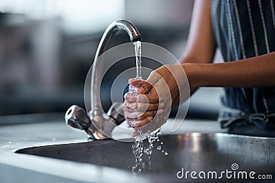 The health inspector would be very proud. a woman washing her hands in the sink of a commercial kitchen. Stock Photo