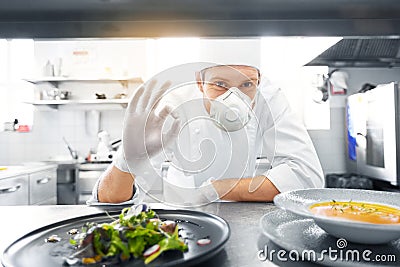 Male chef in mask with food at restaurant kitchen Stock Photo