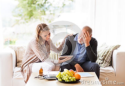 Health visitor and a senior man with tablet during home visit. Stock Photo
