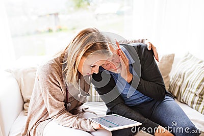 Health visitor and a senior man with tablet during home visit. Stock Photo