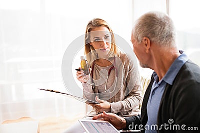 Health visitor and a senior man with tablet during home visit. Stock Photo