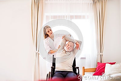 Nurse and senior man in wheelchair during home visit. Stock Photo