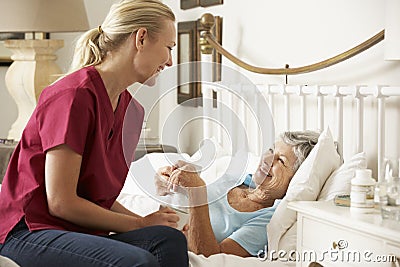 Health Visitor Talking To Senior Woman Patient In Bed At Home Stock Photo