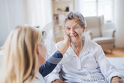 A health visitor talking to a sick senior woman sitting on bed at home. Stock Photo