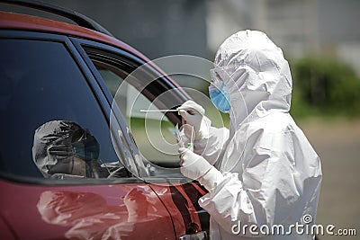 A health worker uses a CPR test mouth and nasal swab on a person inside a car to determine the presence or absence of the Covid- Editorial Stock Photo