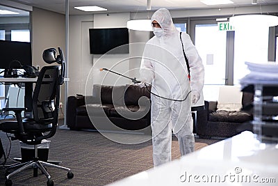 Health worker wearing protective clothes cleaning the office using disinfectant Stock Photo