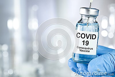 Healthcare cure with a hand in blue medical gloves holding Coronavirus, Covid 19 virus, vaccine vial Stock Photo