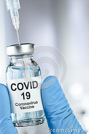 Healthcare cure with a hand in blue medical gloves holding Coronavirus, Covid 19 virus, vaccine vial Stock Photo