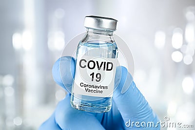 Healthcare cure with a hand in blue medical gloves holding Coronavirus, Covid 19 virus, vaccine vial Stock Photo