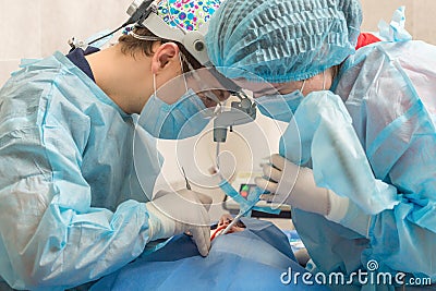 Healthcare, medicine. Young woman with dentist in mask with loupe binoculars in a dental surgery. Stock Photo