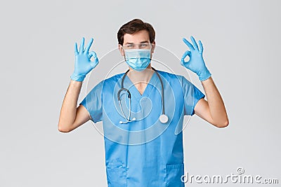 Healthcare workers, coronavirus quarantine campaign and pandemic concept. Smiling handsome doctor in scrubs, intern Stock Photo