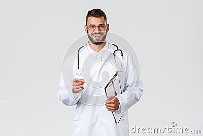 Healthcare workers, medical insurance and covid-19 concept. Handsome doctor in glasses and scrub, holding cliboard and Stock Photo