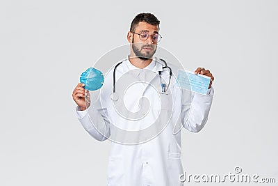 Healthcare workers, medical insurance, pandemic and covid-19 concept. Indecisive male doctor in white coat and glasses Stock Photo