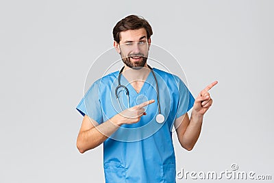 Healthcare workers, pandemic and coronavirus outbreak concept. Handsome cheeky doctor in medical scrubs, stethoscope Stock Photo