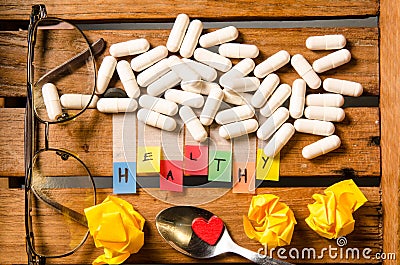 Healthy alphabet and capsule drug with glasses and red heart on wood background Stock Photo