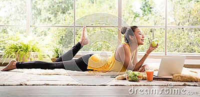 Healthy Asian woman lying on the floor eating salad looking relaxed and comfortable Stock Photo