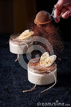 Healthy Banana Mousse or Pudding with Sifting Cocoa on Dark Background Stock Photo