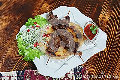 Healthy barbecued lean cubed pork kebabs served with a corn tortilla and fresh lettuce and tomato salad, close up view Stock Photo