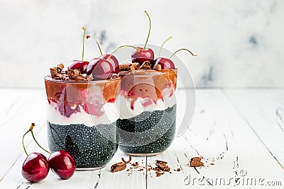 Healthy Black Forest dessert. Black activated charcoal chia pudding with cherries, coconut cream and chocolate. Vegan breakfast Stock Photo