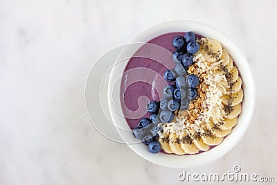 Blueberry smoothie bowl with coconut, bananas, chia seeds and granola, above view on a marble Stock Photo