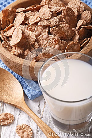 Healthy bran flakes in a wooden bowl and milk close-up. Vertical Stock Photo
